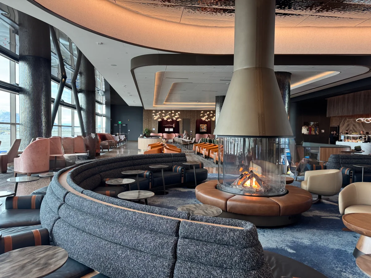 Delta Sky Club lounge featuring a circular fire pit, leather banquettes, and a designed ceiling at SLC